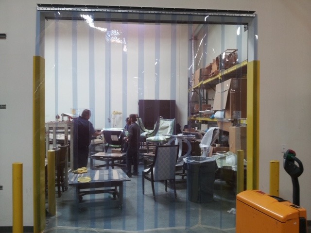 A work area visible through a clear plastic strip curtain