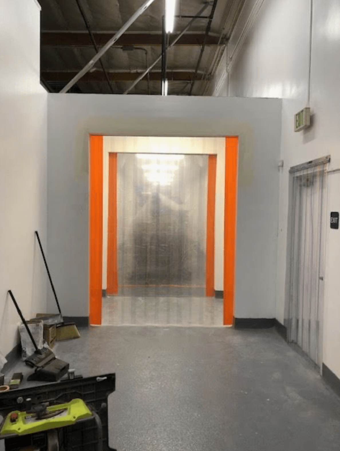 Clear plastic curtain doors hang in an orange-framed entrance